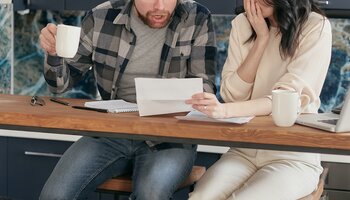 Shocked look on man's face. Looking at paper held by woman.